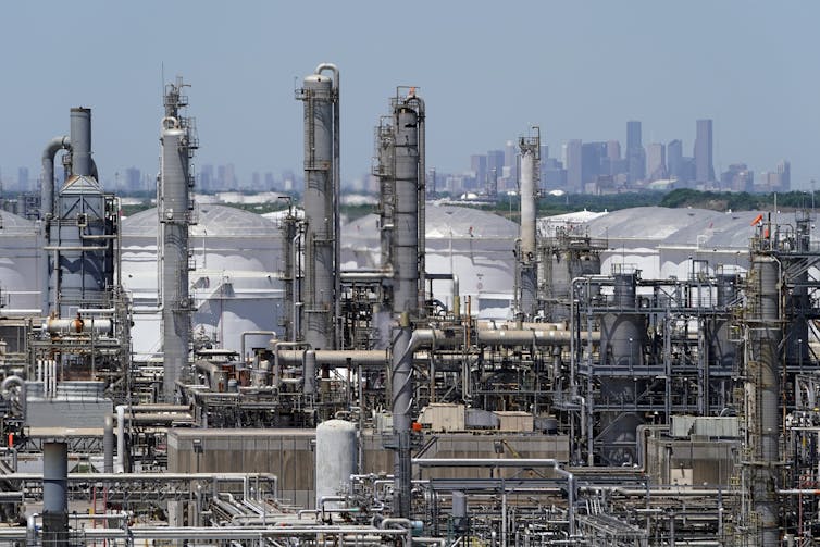 A view across refineries and oil storage tanks along the ship channel, with Houston on the horizon. The entire area is flat.