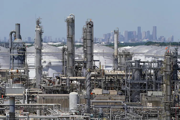 A view across refineries and oil storage tanks along the ship channel, with Houston on the horizon. The entire area is flat.