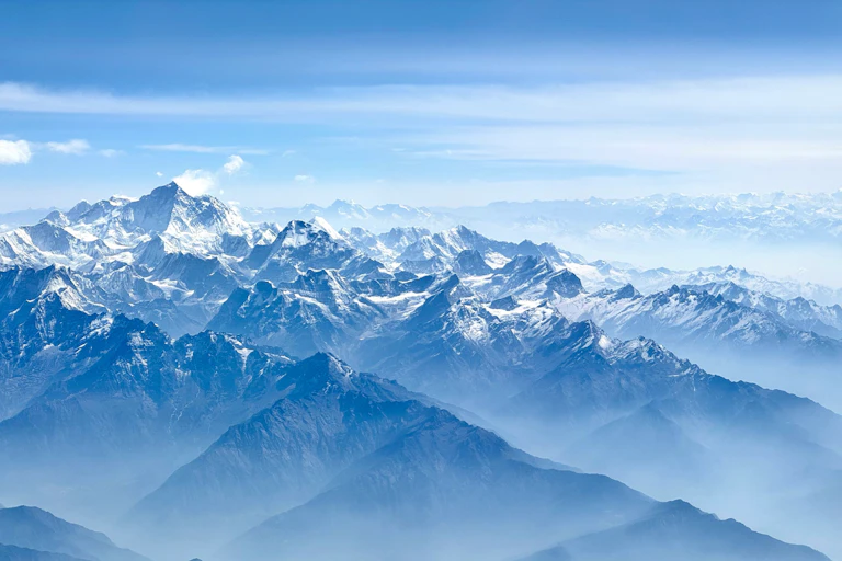 Aerial photo of a snow-covered mountain range, with one particularly prominent peak.