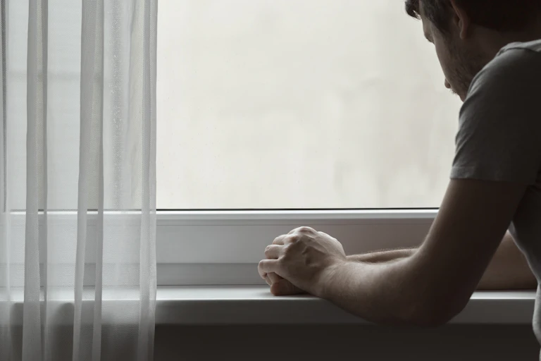 A young man stares out a window