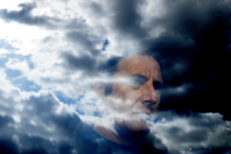 Man's face superimposed over a brooding cloudy sky