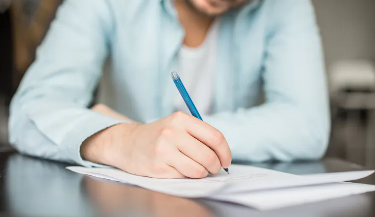 A man writes on a sheet of paper.