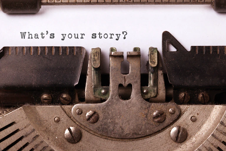 A close up of a typewriter, saying 'What's your story?'
