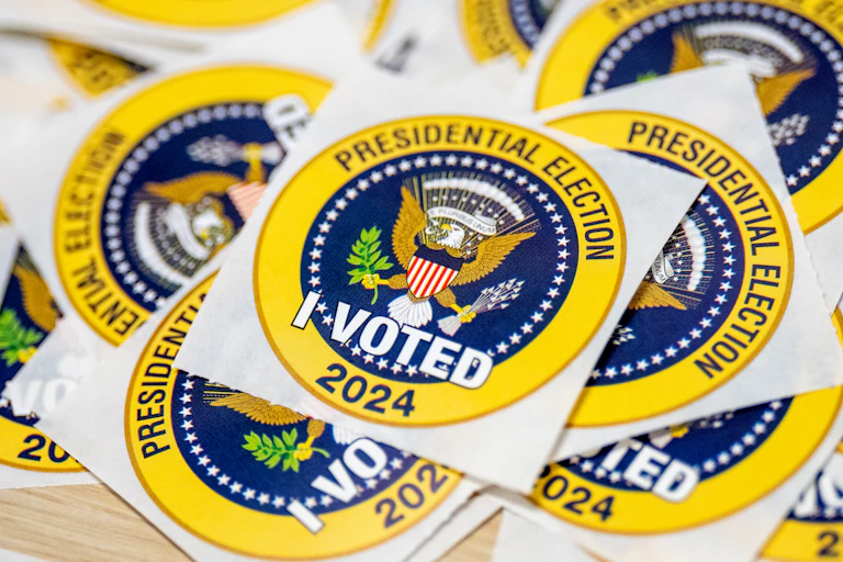 Pegatinas de color amarillo brillante y azul con el sello presidencial que dicen 'ELECCIÓN PRESIDENCIAL 2024' y 'YO VOTO'.