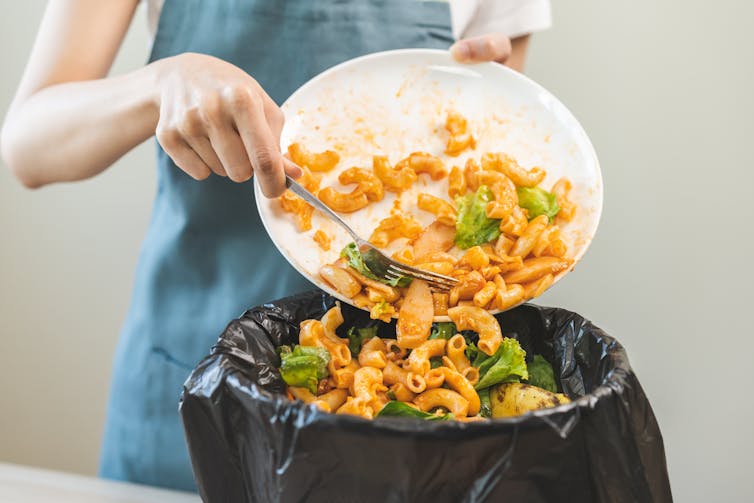 woman scrapes food into bin