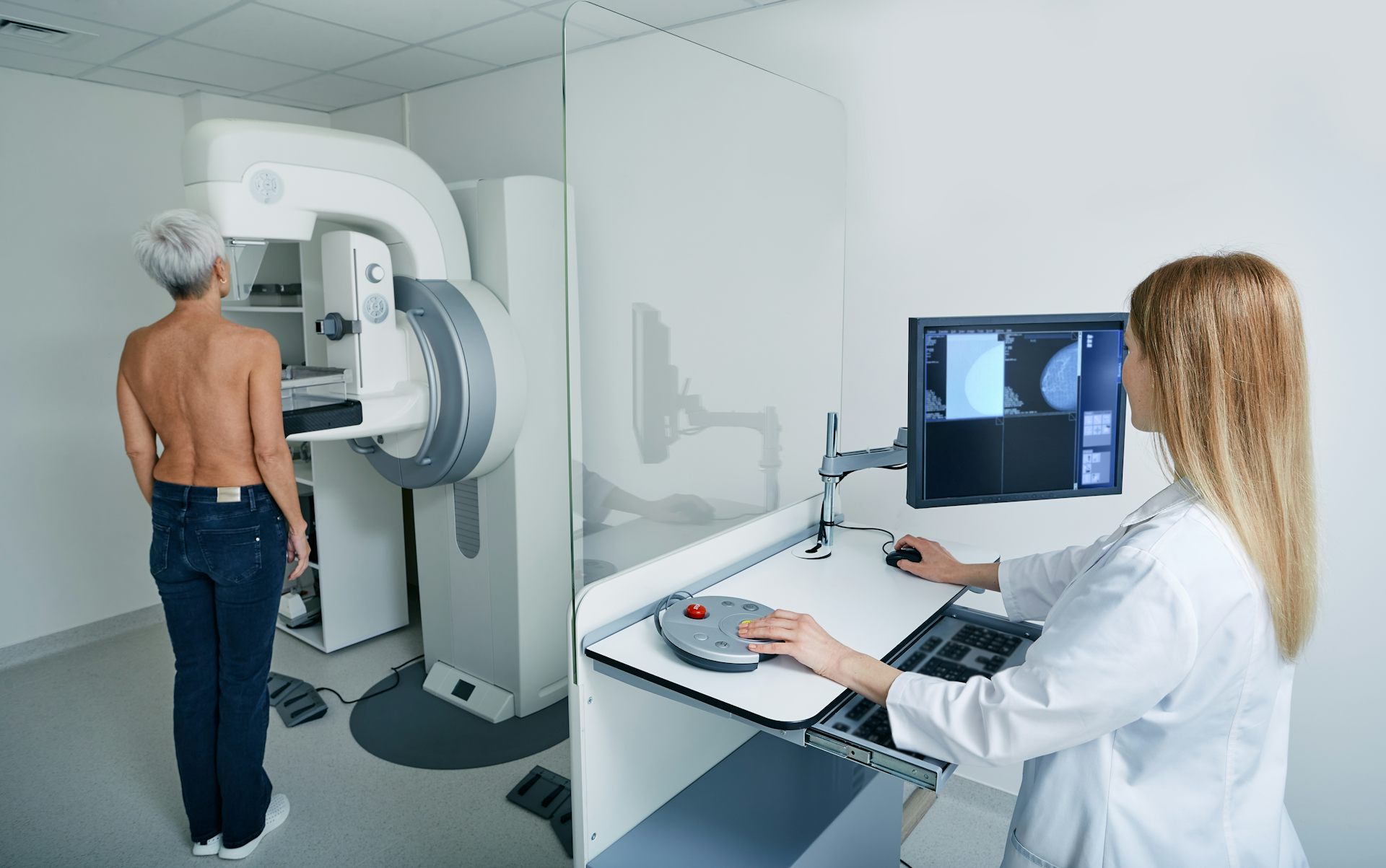 Une femme effectuant une mammographie sous la supervision d’une médecin.