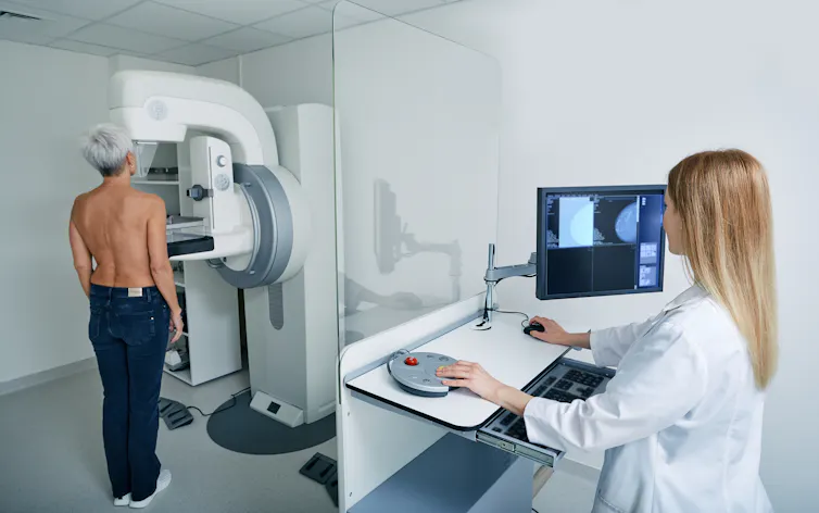 Une femme effectuant une mammographie sous la supervision d’une médecin.