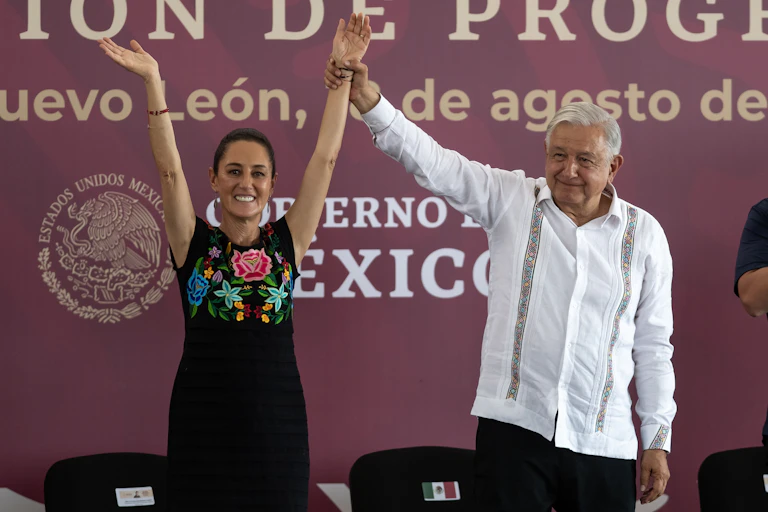 Andres Manuel Lopez Obrador holding Sheinbaum's arms aloft in celebration.