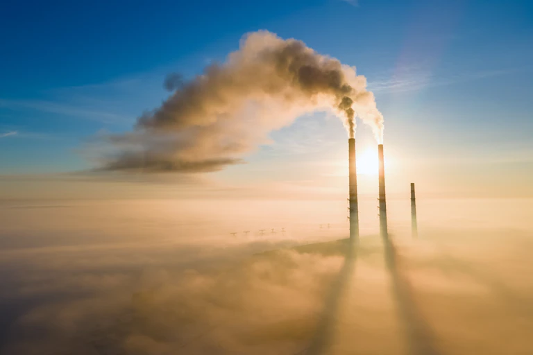 chimneys at a coal power plant pumping out smoke and greenhouse gases into the sky
