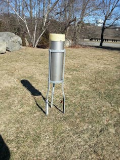 A large metal tube in a bracket in the middle of a field.