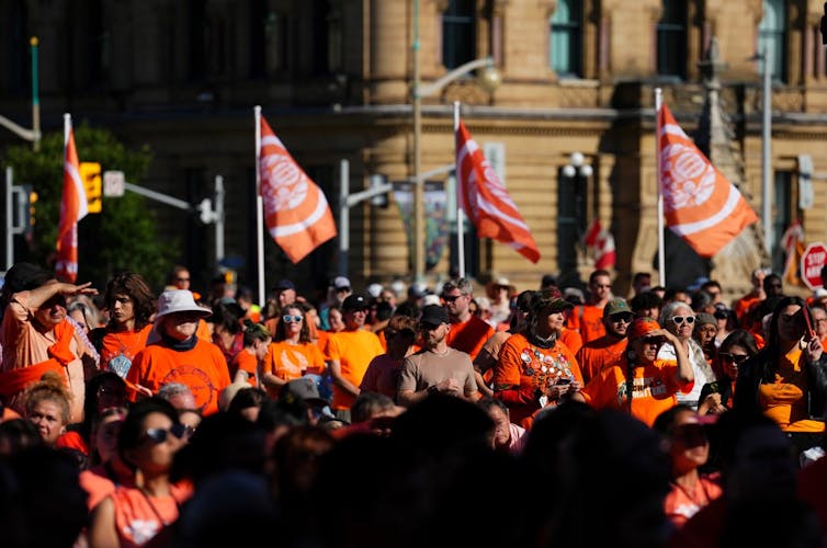Des gens revêtant des chandails orange tiennent un rassemblement