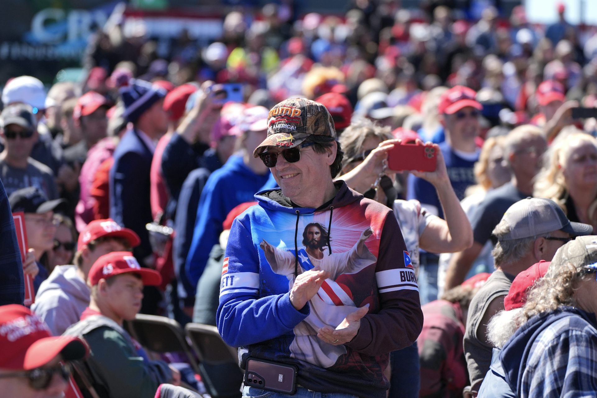 Un homme portant un chandail représentant un Jésus aux couleurs du drapeau états-unien participe à un rassemblement politique.