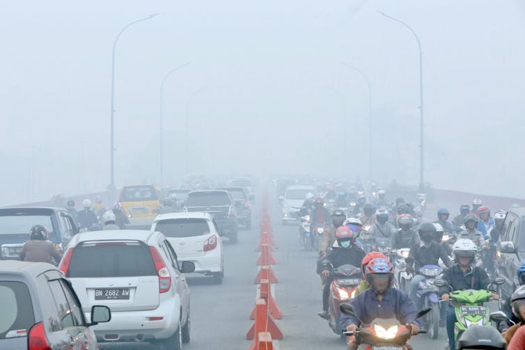 Motorists drive down a highway with heavily polluted skies.