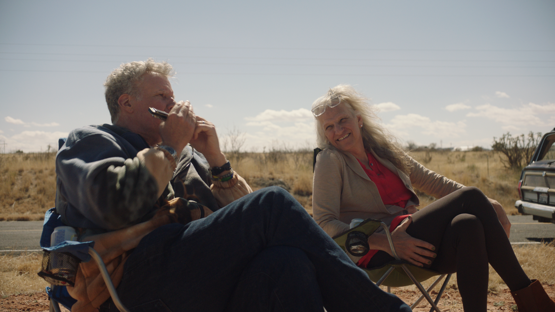 Ferrell and Steele sat on camping chairs smiling at each other.