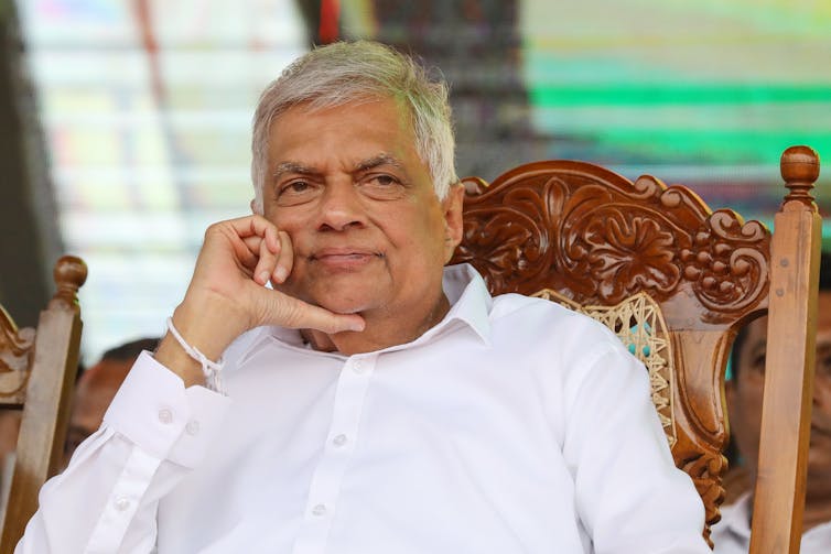 Ranil Wickremesinghe sat in a wooden chair.