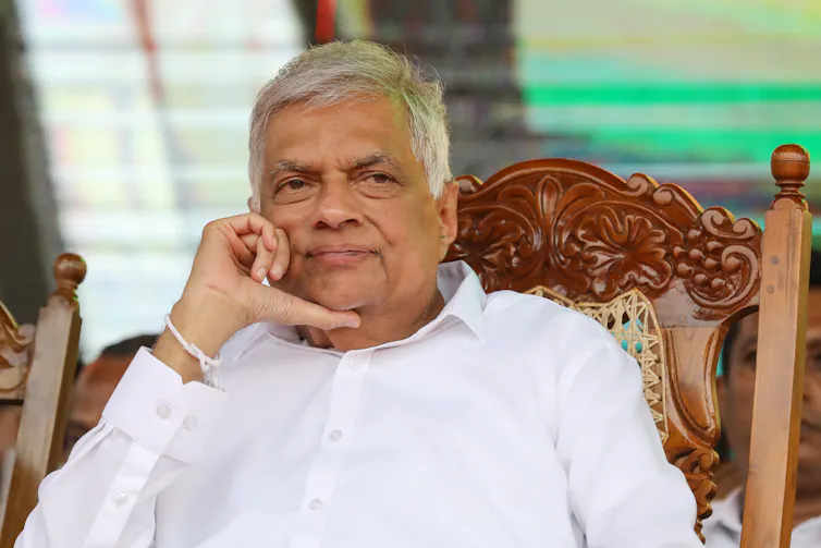 Ranil Wickremesinghe sat in a wooden chair.