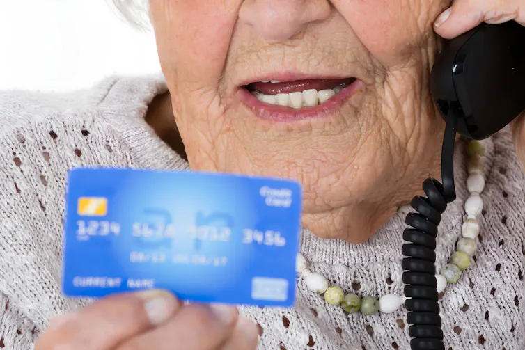 An elderly woman giving her credit card details over the phone