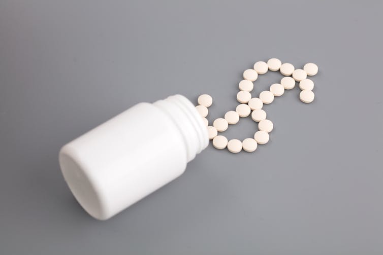 A pill bottle with pills arranged in the shape of a dollar sign