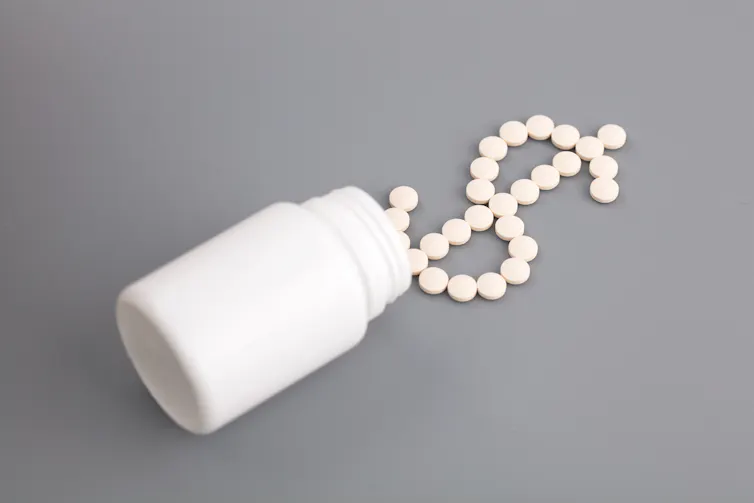 A pill bottle with pills arranged in the shape of a dollar sign