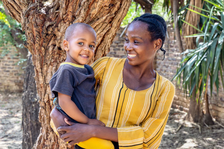 A young black mother carrying a child in her arms