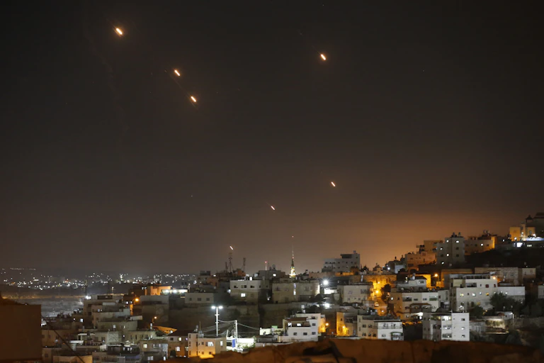 Yellow dots appear to fall from a dark sky over buildings.