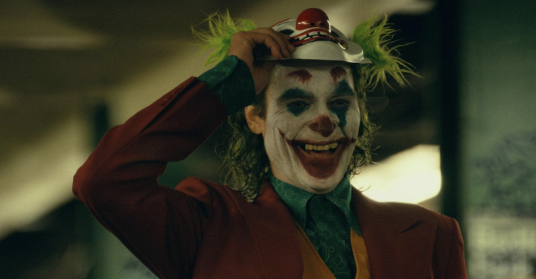 man in clown face paints lifts clown mask off his face