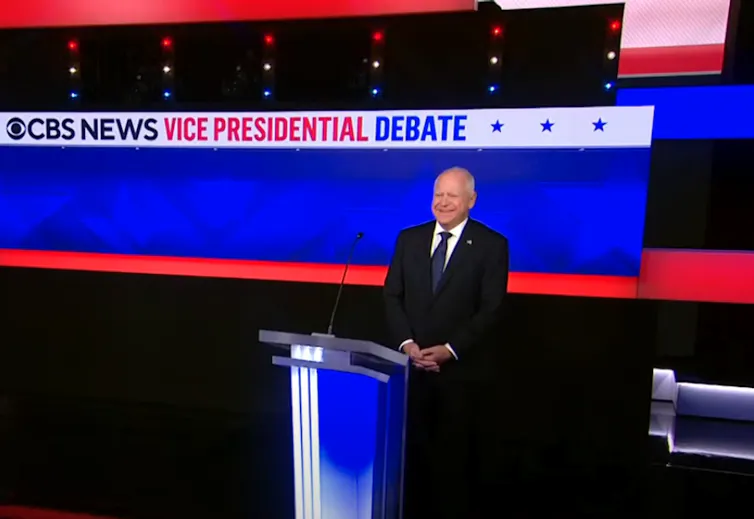 Bald man stands at lectern and smiles.