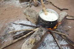 A pot of porridge cooking on a wood fire