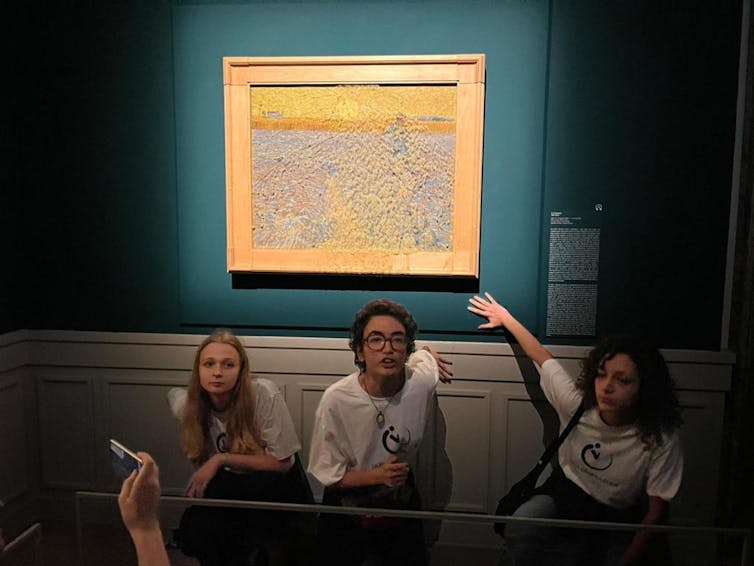 Three people sat underneath painting