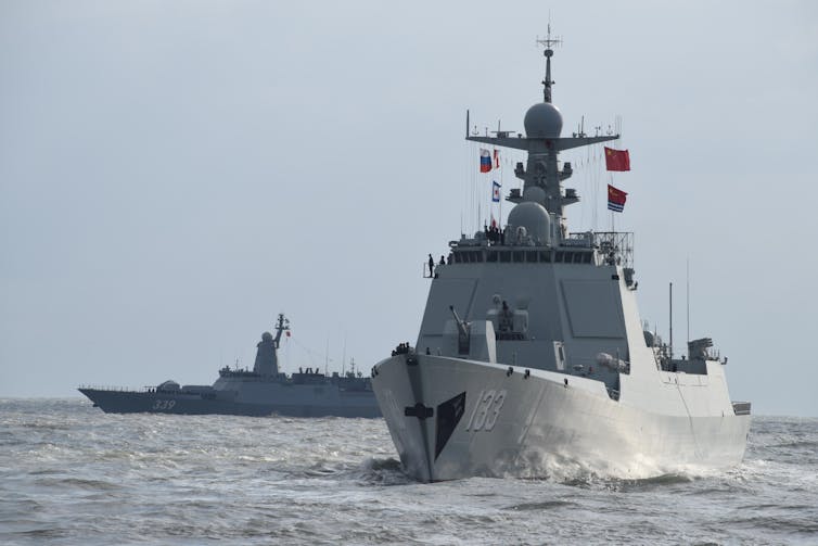 Two large warships are seen in waters.