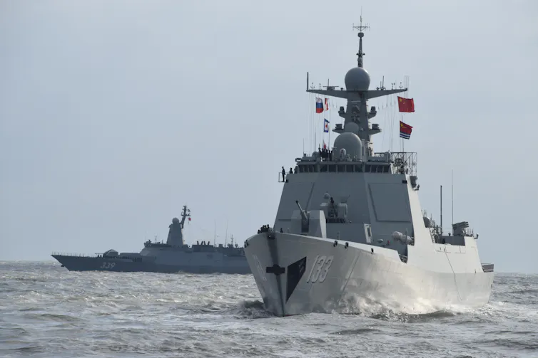 Two large warships are seen in waters.