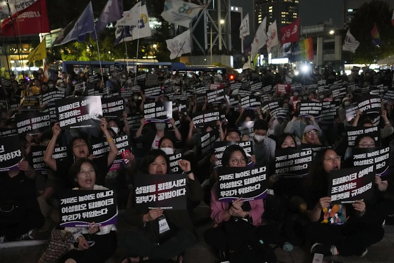 Multidões de ativistas seguram cartazes em uma manifestação em Seul, Coreia do Sul, à noite.