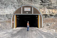 A manager stands in front of the entrance to the Khutala coal mine in South Africa - a large door built into the side of a rocky hill