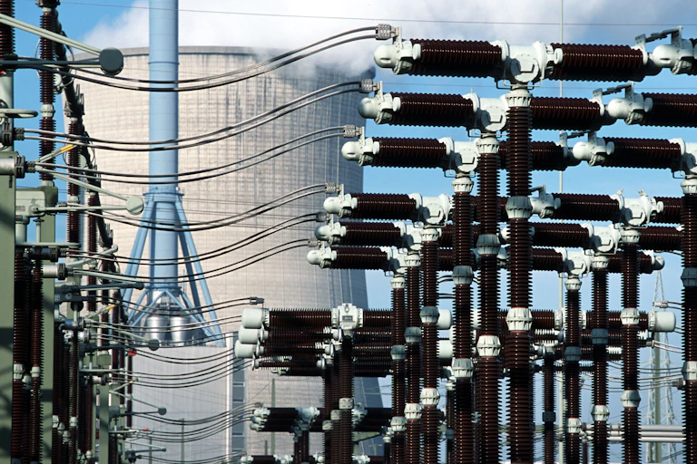 A cooling tower in the background with a substation in the foreground.