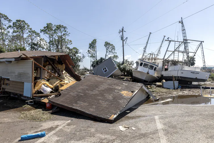 A building demolished by a hurricane, with downed power lines in the background.