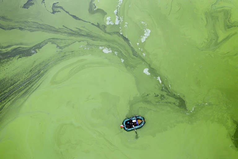 A boat floats on the surface of murky water.
