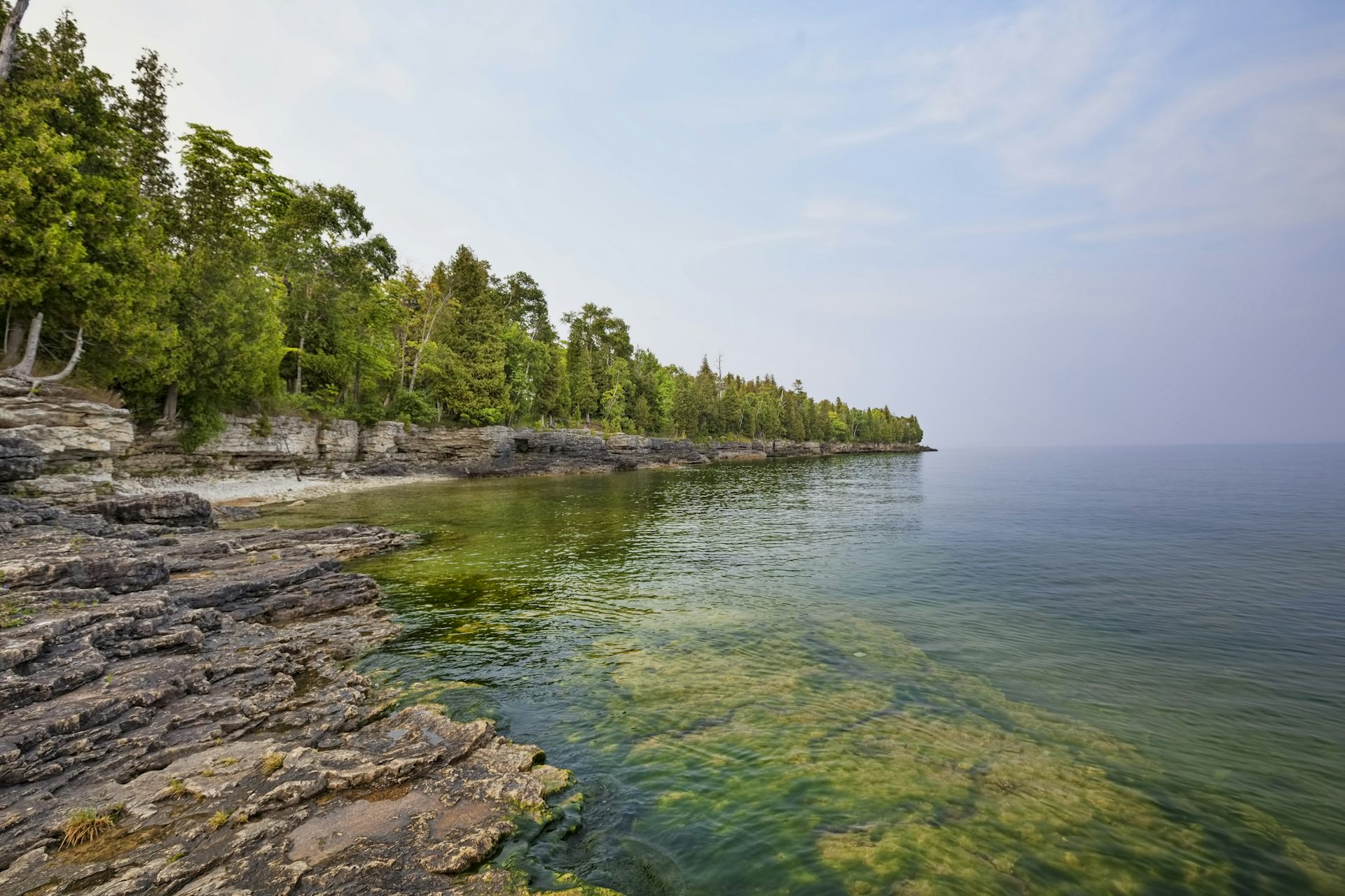Scenic view of limestone cliffs with trees alongside calm body of water