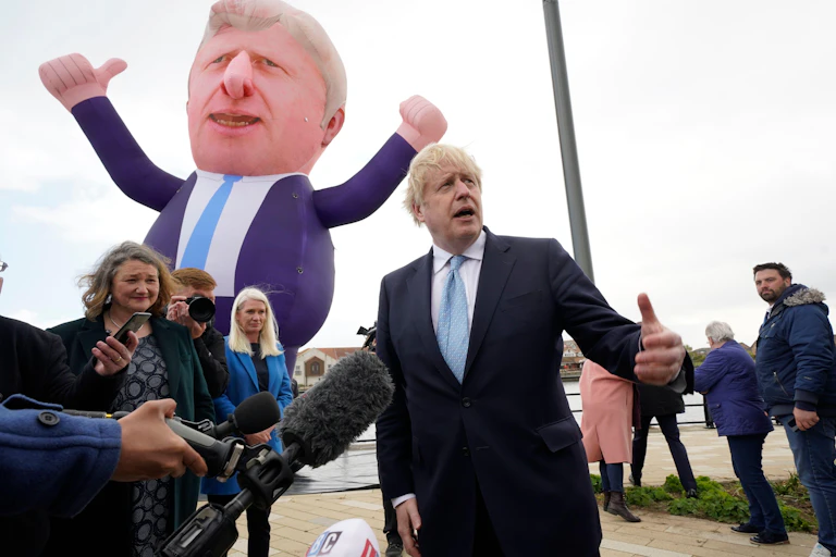 Boris Johnson stands in front of a blow-up version of himself.