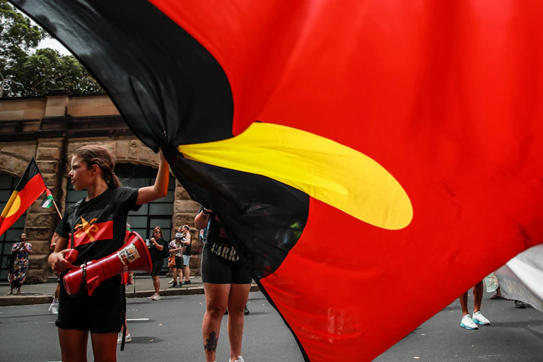Children at a street rally hold a large Aboriginal flag