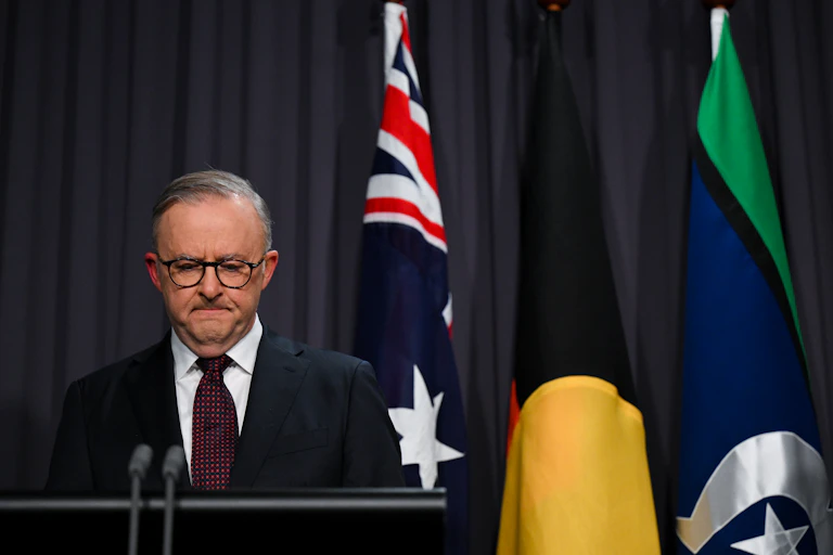 A man in a suit frowns at a lectern