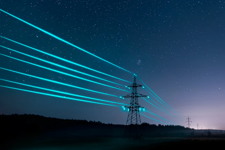 Electricity pylons with glowing wires in night sky