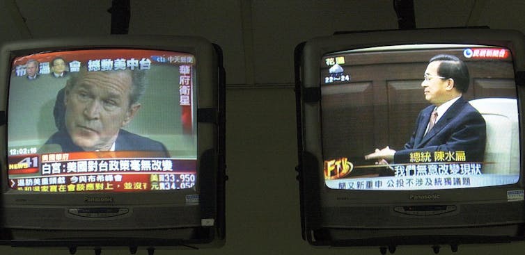 teo television screens show grainy footage of two men.