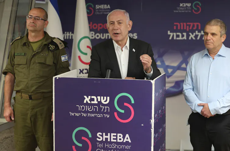 Israeli PM Benjamin Netanyahu, speaks from a podium flanked by military and political aides, June 2024.