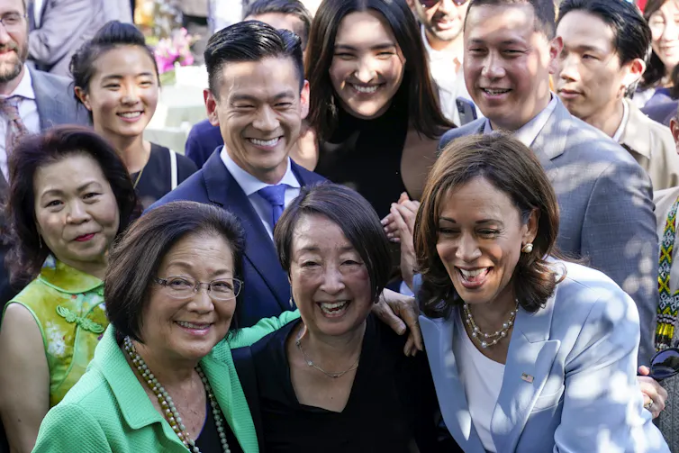 A group of people pose together for a photo and smile, all dressed in formal clothing.