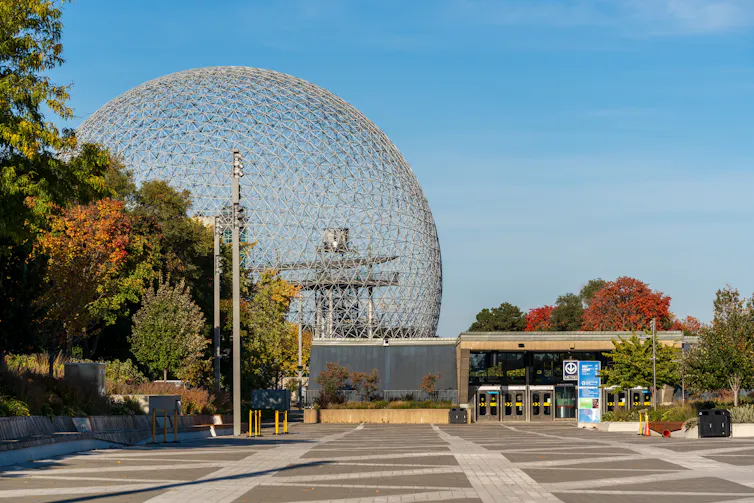 A large, glass sphere is seen behind trees and a metro station
