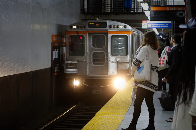 People stand on subway platform as train pulls into station