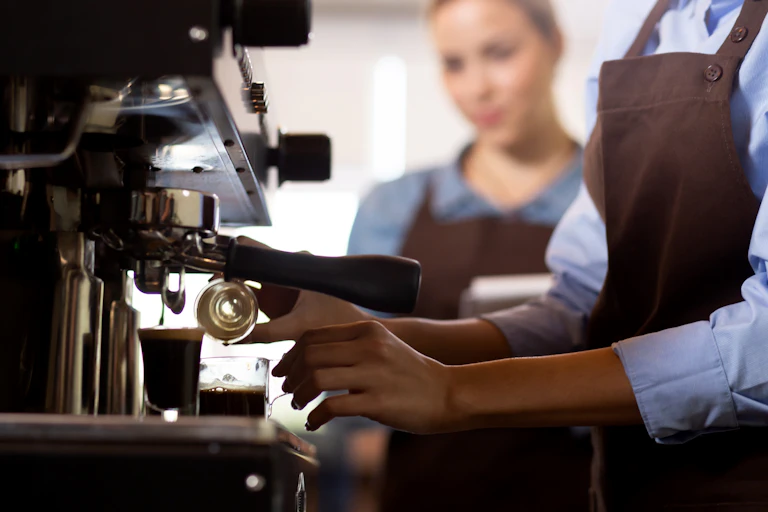 Closeup hands of barista preparing coffee on an espresso machine