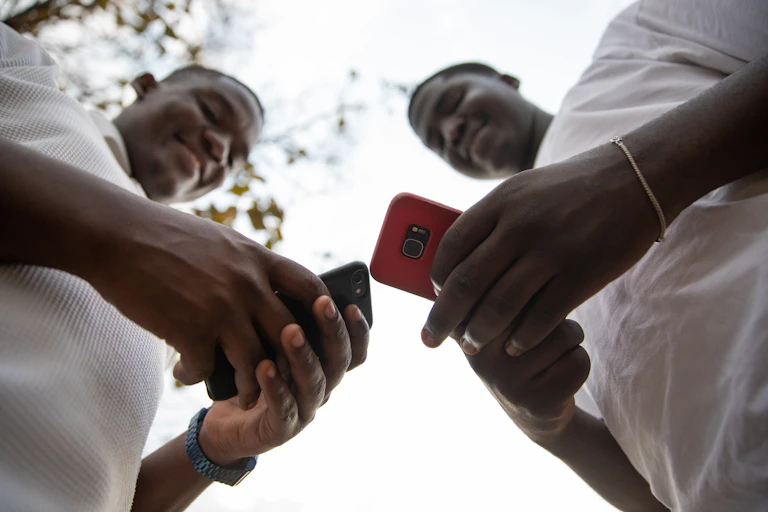 Two smiling young men looking at their cellphones