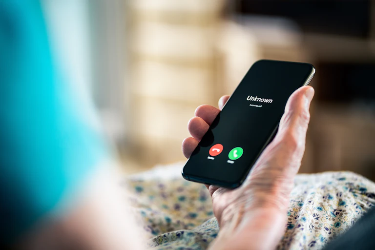 An elderly person's hand holds a cell phone.