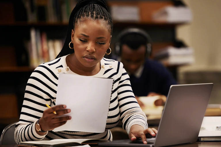 Young woman reads a document while seated at a computer